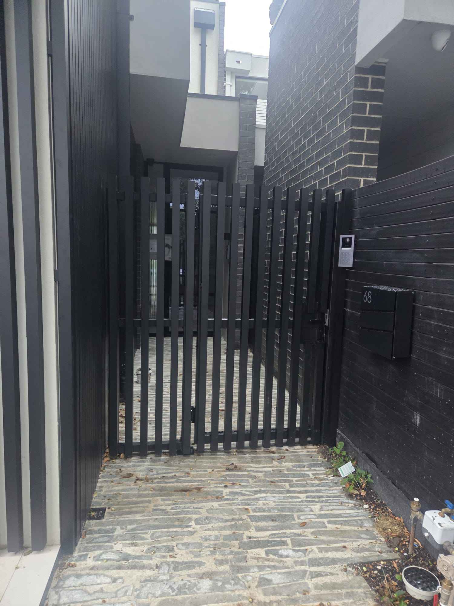 Slat entry gate between brick and timber walls