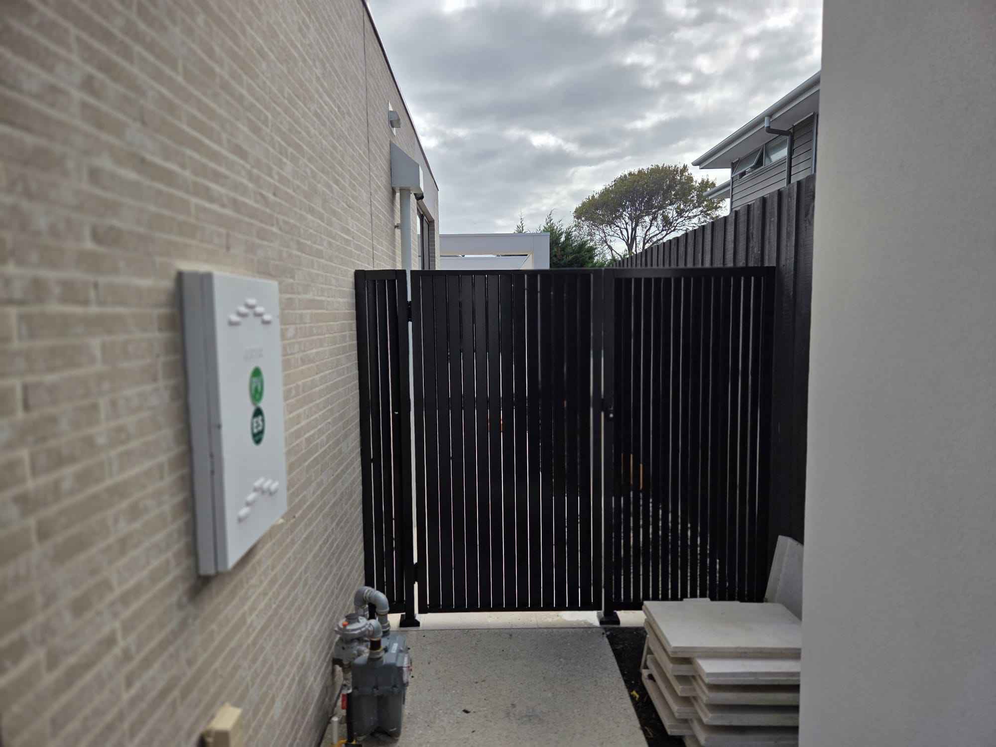 Black slat side gate between masonry walls