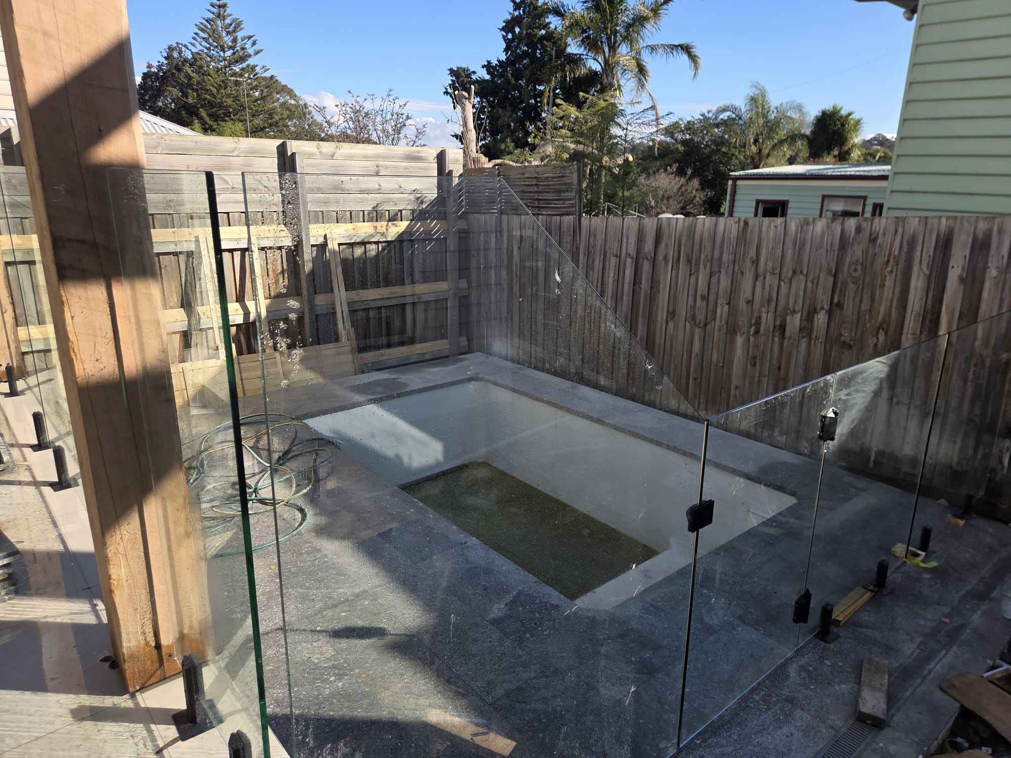 Frameless glass pool fencing around an in-ground pool
