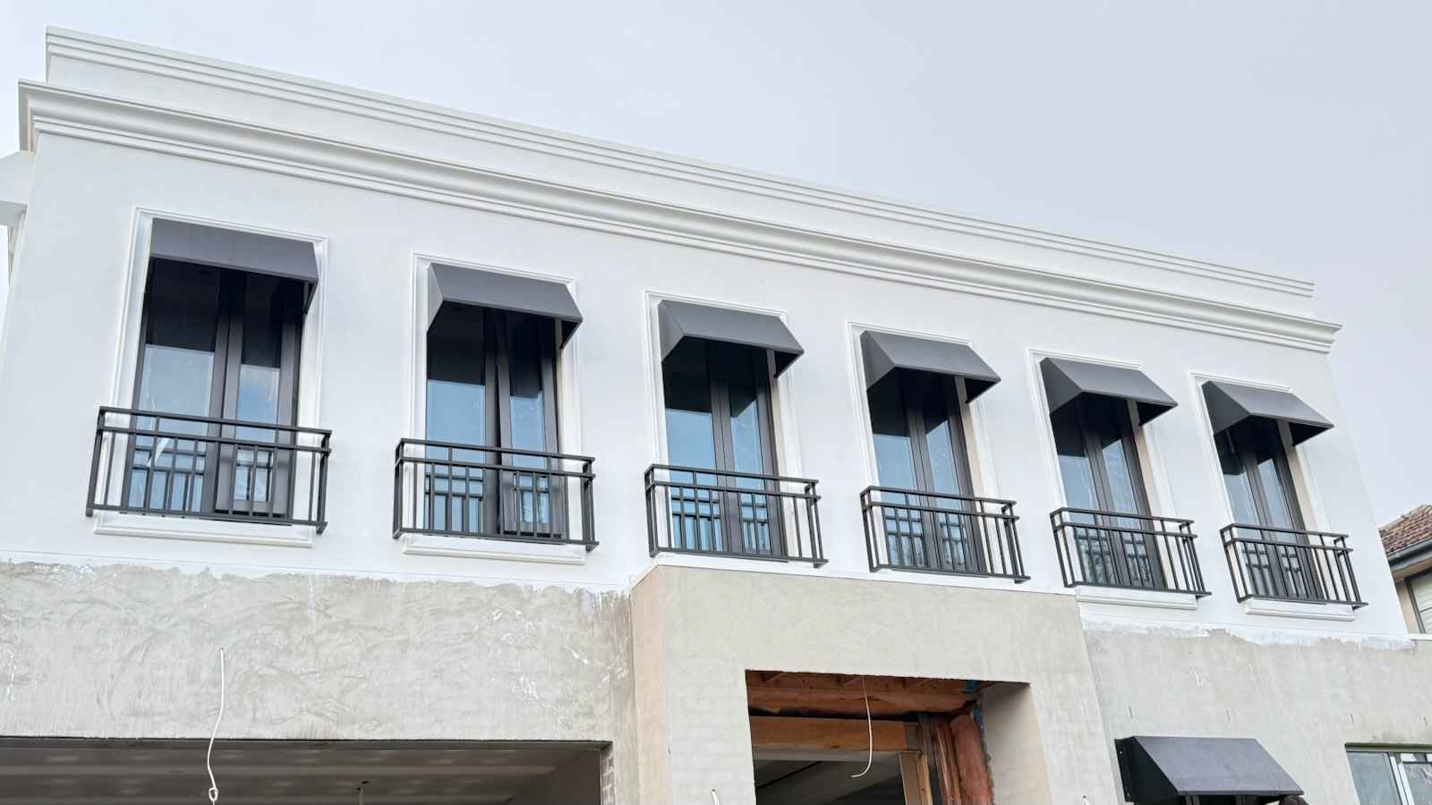Row of wrought iron Juliet balconies under window awnings