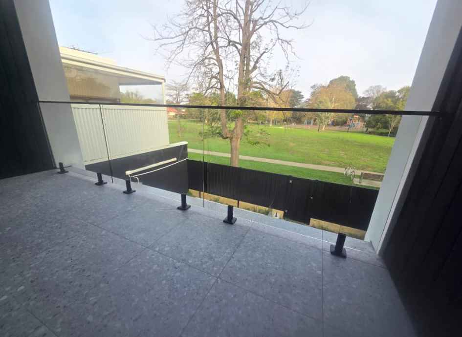 Glass balustrade with black spigots overlooking a park