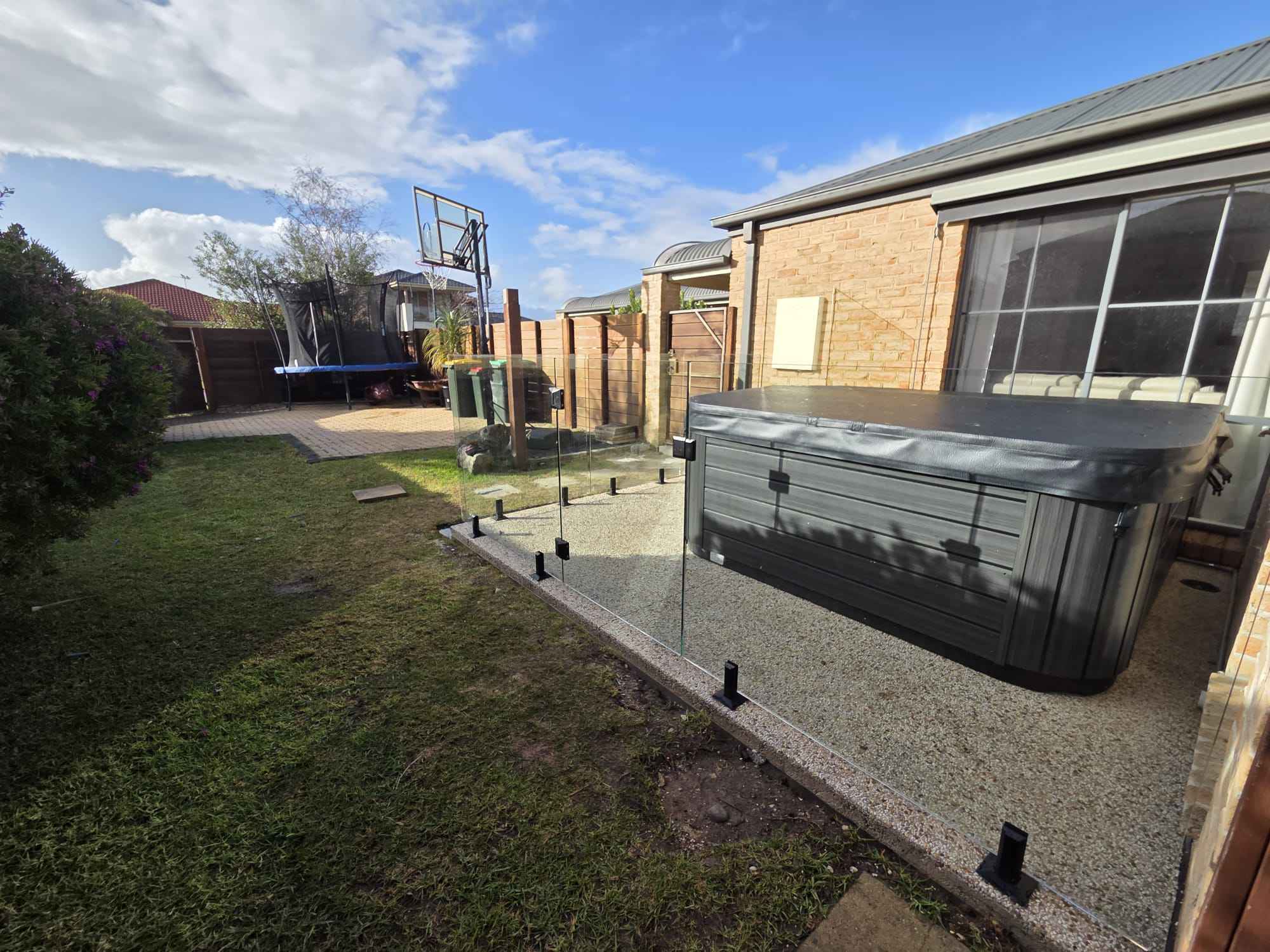 Frameless glass fence around a backyard spa